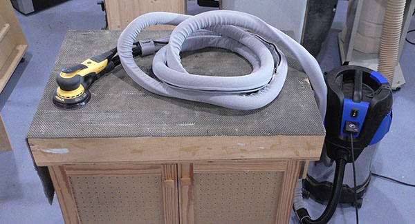 A Mirka Sander with the sander hose and cord wrapped in a Mirka sleeve