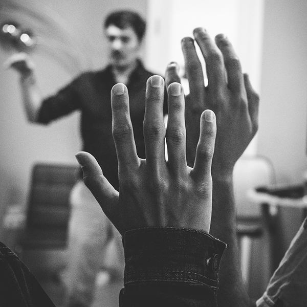 Students hold up their hands in a classroom setting. Photo by Artem Maltsev, Unsplash.com