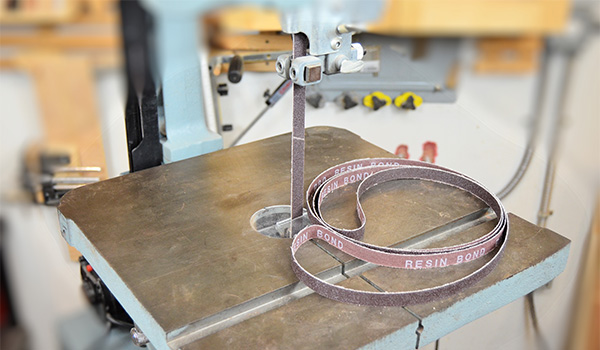 An image of a bandsaw with a spare belt laying on the table