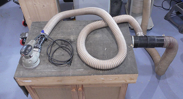 A random orbit sander with the hose and power cord