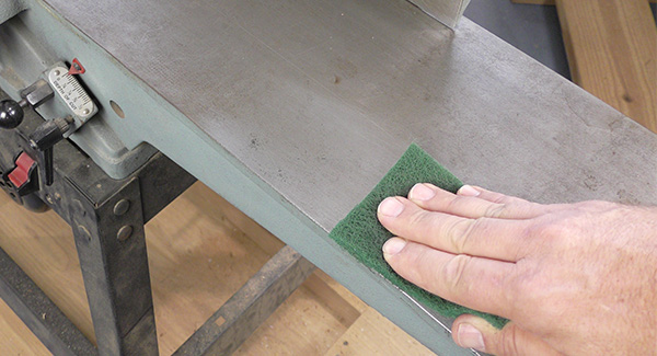 A worker uses a non-woven pad to remove rust from a cast iron top