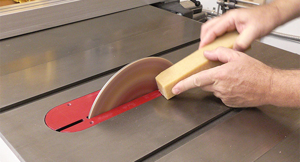 A worker uses an eraser stick to clean a table saw blade