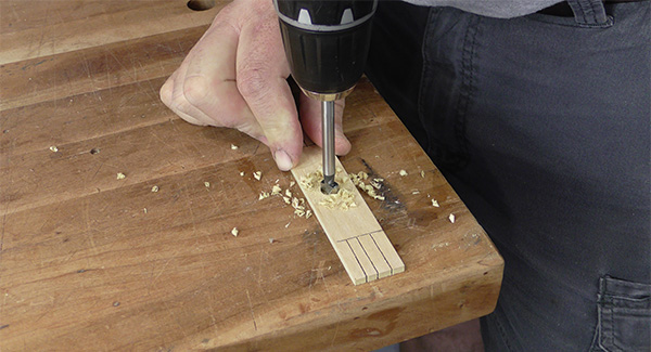 The craftsman drills a hole in the center of the template for making a mop sander.