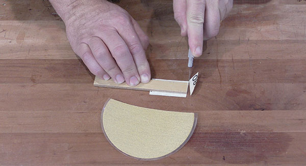 A PSA sanding disc mounted to a backer is cut to make a detail sanding stick