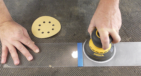 Using the discount sanding disc to sand a piece of acrylic